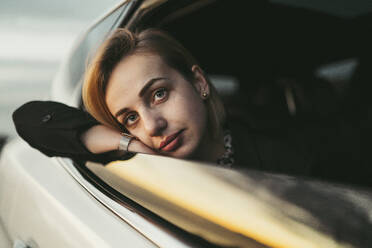 Junge blonde Frau schaut aus dem Autofenster - MTBF00320