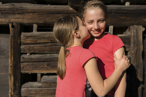 Girl embracing and kissing her sister stock photo