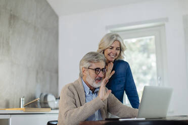 Älterer Mann mit Frau benutzt Laptop auf Küchentisch zu Hause - SODF00555