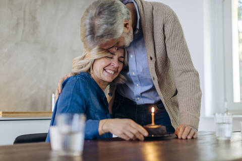 Älteres Paar feiert Geburtstag mit Kuchen in der Küche zu Hause, lizenzfreies Stockfoto