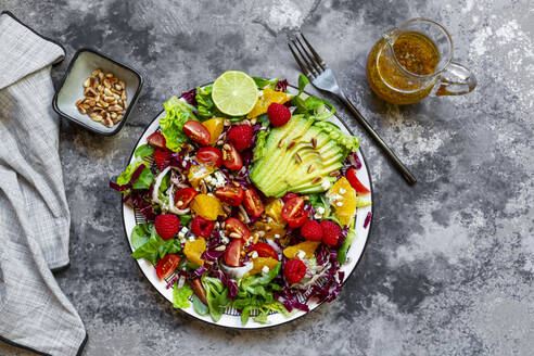 Studio shot of fruity salad plate with lambs lettuce, radicchio, lettuce hearts, avocado, tomato, pine nuts, raspberries, oranges, lime - SARF04429