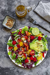 Studio shot of fruity salad plate with lambs lettuce, radicchio, lettuce hearts, avocado, tomato, pine nuts, raspberries, oranges, lime - SARF04431