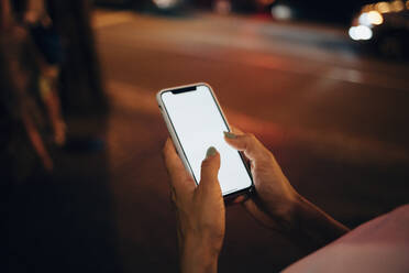 Hands of woman holding smartphone at night, close-up - OYF00089