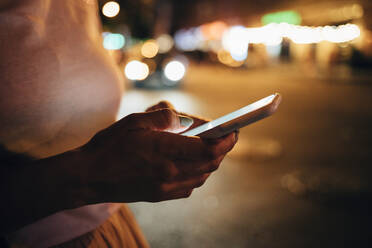 Hände einer Frau, die nachts ein Smartphone hält, Nahaufnahme - OYF00095