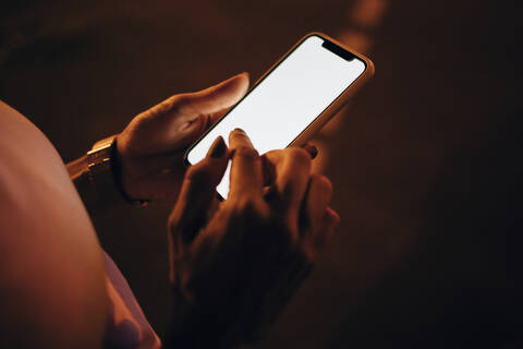 Hände einer Frau, die nachts ein Smartphone hält, Nahaufnahme, lizenzfreies Stockfoto