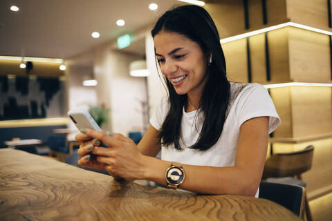 Schwarzhaarige Frau benutzt Smartphone in einem Cafe, lizenzfreies Stockfoto