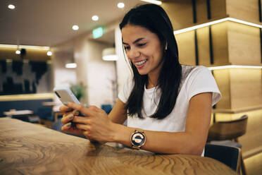 Schwarzhaarige Frau benutzt Smartphone in einem Cafe - OYF00099