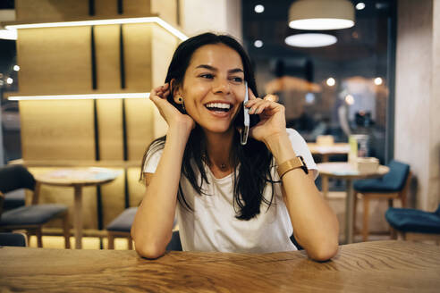 Schwarzhaarige Frau benutzt Smartphone in einem Cafe - OYF00100