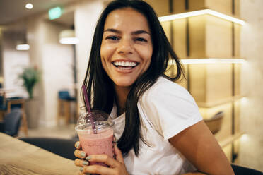 Schwarzhaarige Frau trinkt einen Smoothie in einem Cafe - OYF00110