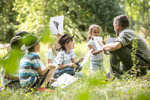 Schulkinder, die Naturkunde betreiben und Bilder von Tieren halten, lizenzfreies Stockfoto