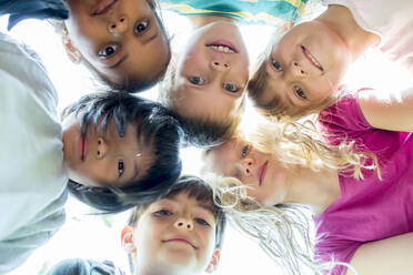 Group of children, sticking heads together, upward view - WESTF24436