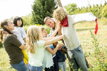 Schulkinder auf einem Ausflug, die eine Vogelscheuche auf einem Feld bauen - WESTF24452