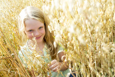 Lächelndes Mädchen steht in einem reifen Weizenfeld - WESTF24462