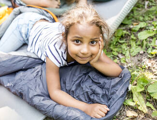 Little girl lying on sleeping bag, looking at camera - WESTF24487