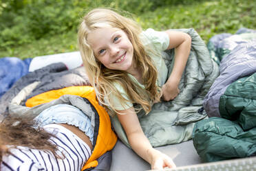 Little girl lying on sleeping bag, looking at camera - WESTF24488