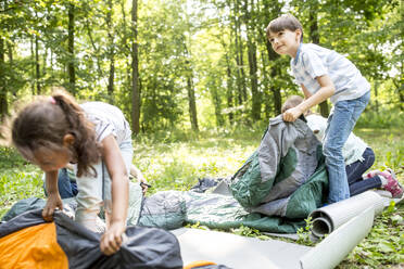 Schulkinder packen ihre Schlafsäcke aus, um im Wald zu zelten - WESTF24492