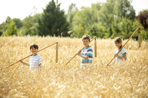 Kinder lernen auf einem Feld, wie man Weizen drischt - WESTF24532