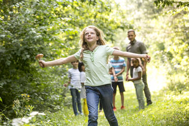 School children walking in forest with their teacher, girl running, holding mushroom - WESTF24542