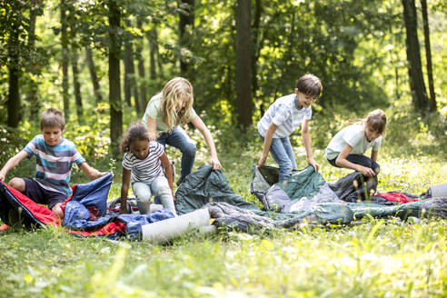 Schulkinder packen ihre Schlafsäcke aus, um im Wald zu zelten - WESTF24552