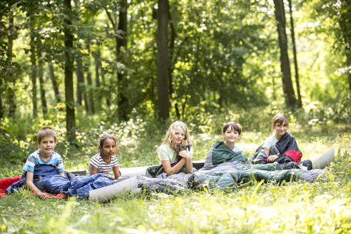 kinder zelten im Wald, in ihren Schlafsäcken sitzend - WESTF24553