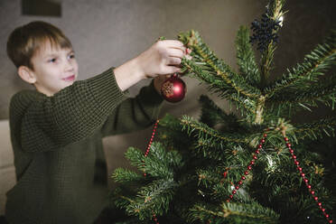 Junge beim Schmücken des Weihnachtsbaums - EYAF00821