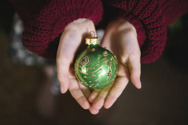 Grünes Weihnachtsornament in der Hand eines Mädchens - EYAF00829