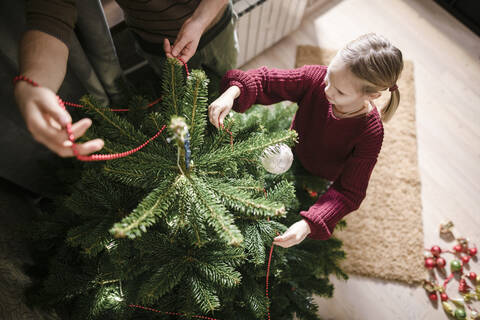 Vater und Tochter schmücken den Weihnachtsbaum, von oben, lizenzfreies Stockfoto
