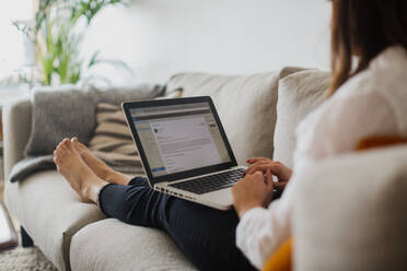 Frau benutzt Laptop auf Sofa - JOHF05315