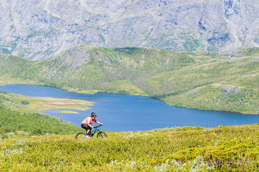Woman riding bike in mountains - JOHF05399