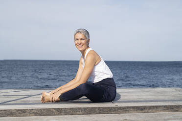 Frau übt Yoga auf dem Steg - JOHF05492