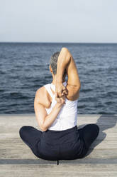 Woman practicing yoga on pier - JOHF05498