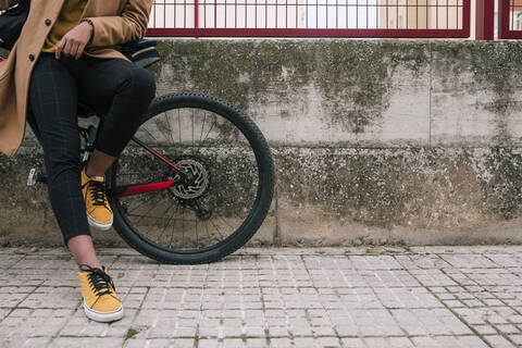 Tiefschnitt eines stilvollen jungen Mannes mit Fahrrad in der Stadt, lizenzfreies Stockfoto