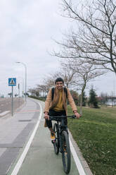 Portrait of smiling young man riding bicycle in the city - GRCF00086