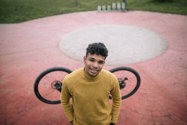 Porträt eines lächelnden jungen Mannes mit Fahrrad im Freien - GRCF00095