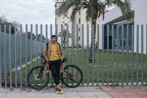 Porträt eines lächelnden jungen Mannes mit Fahrrad in der Stadt - GRCF00103