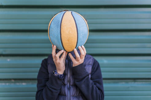 Junge bedeckt sein Gesicht mit einem Basketball - DLTSF00409