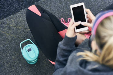 Junge Frau benutzt Smartphone nach dem Training, Blick von oben - ABIF01245