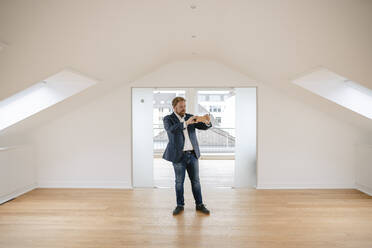 Estate agent standing in empty apartement taking pictures - GUSF03181