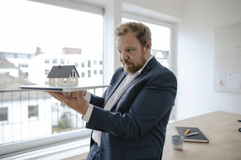 Geschäftsmann hält Modellhaus im Büro - GUSF03185