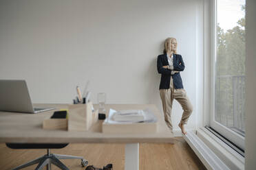 Junge Geschäftsfrau im Büro schaut aus dem Fenster - GUSF03187