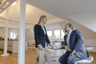 Geschäftsmann und Geschäftsfrau unterhalten sich an einer Tischtennisplatte im Büro - GUSF03206
