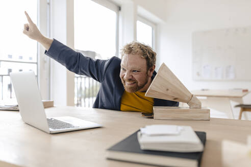 Glücklicher Geschäftsmann im Büro, der mit einem Holzgrammophon Musik hört - GUSF03240