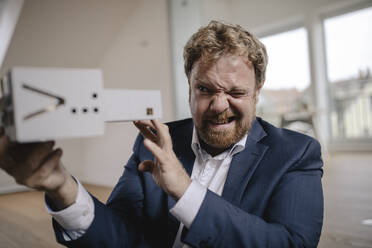 Twinkling businessman holding architectural model in office - GUSF03246