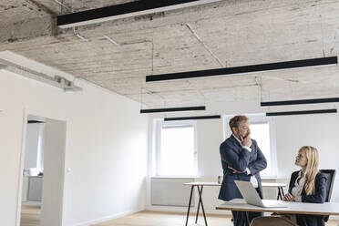 Businessman and businesswoman talking at desk in office - GUSF03276