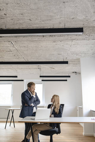 Geschäftsmann und Geschäftsfrau im Gespräch am Schreibtisch im Büro, lizenzfreies Stockfoto