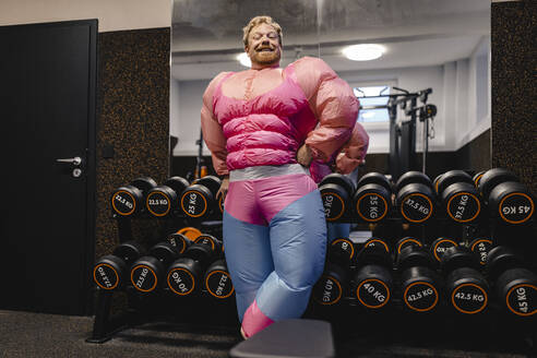 Proud man wearing pink bodybuilder costume in gym - GUSF03288