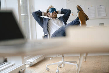 Businessman having a power nap at desk in office - GUSF03298