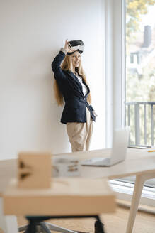 Lächelnde junge Geschäftsfrau mit VR-Brille im Büro - GUSF03305