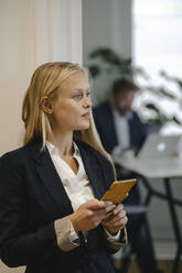Young businesswoman with cell phone in office - GUSF03322