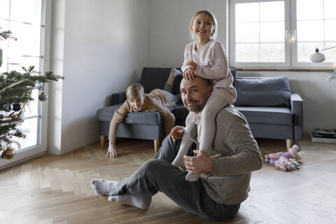 Porträt eines reifen Mannes, der zu Hause auf dem Boden sitzt und mit seiner kleinen Tochter spielt, lizenzfreies Stockfoto